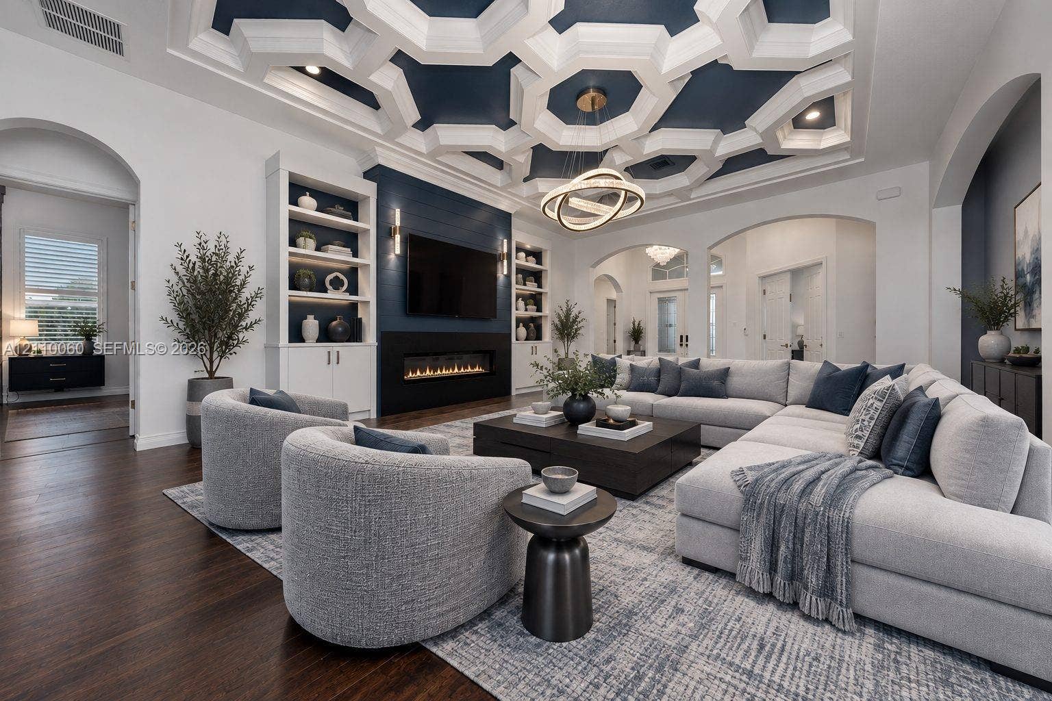 Virtually staged. Living area featuring an intricate geometric coffered ceiling, linear fireplace with a shiplap surround, built-in shelving, hardwood flooring, and arched doorways