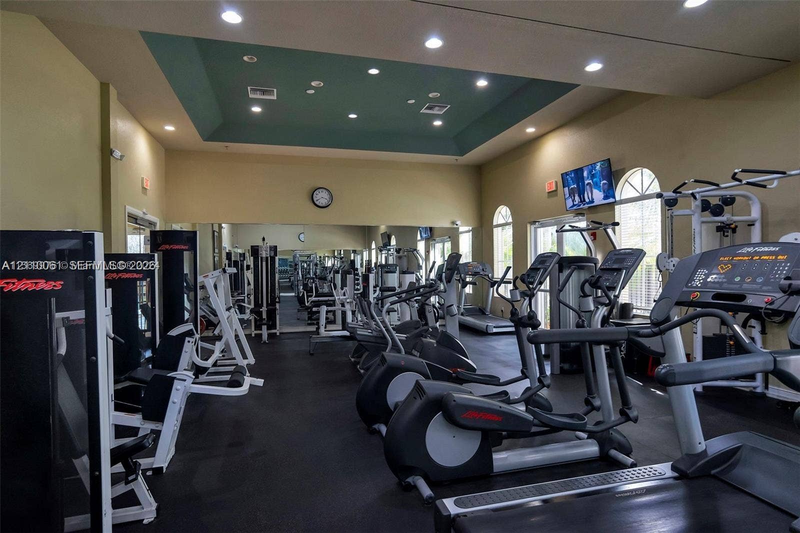 4424 E Whitewater Avenue, Weston, FL 33332 Fitness center featuring a tray ceiling with recessed lighting, wall-to-wall mirrors, and arched windows