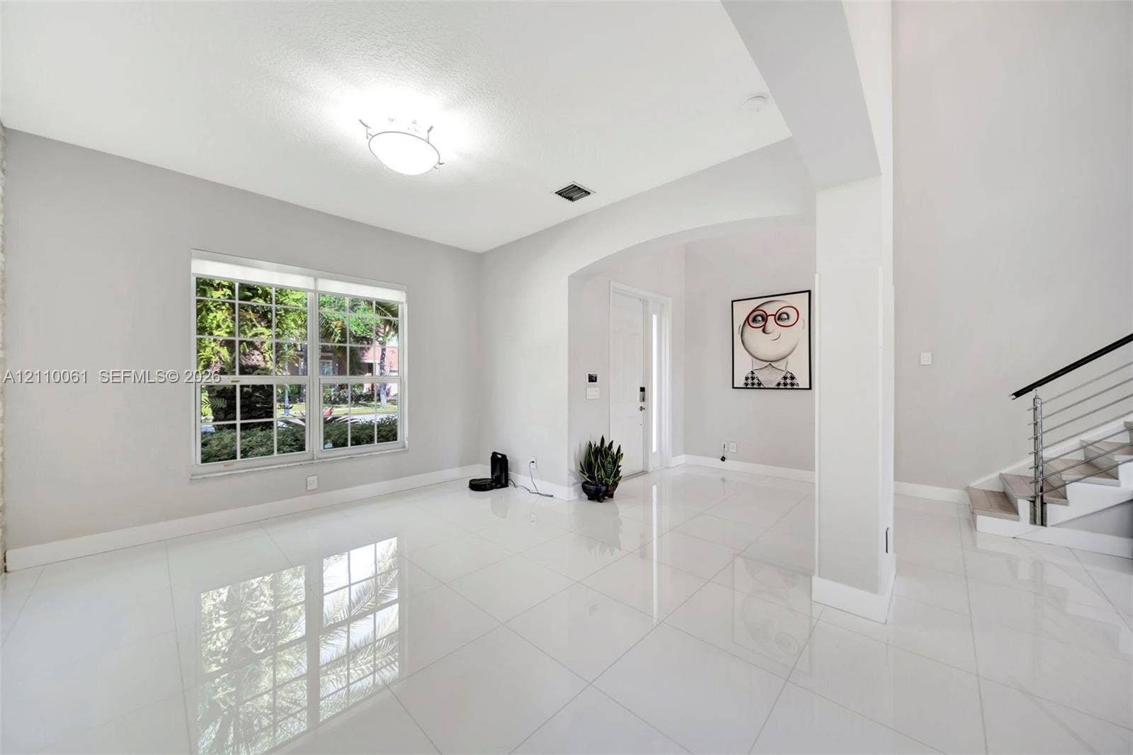 4424 E Whitewater Avenue, Weston, FL 33332 High-gloss tile flooring, arched architectural opening, multi-pane window, and staircase featuring a metal railing system