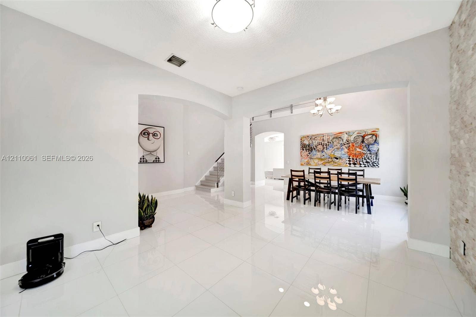 4424 E Whitewater Avenue, Weston, FL 33332 Polished tile flooring, neutral wall tones, arched entryways, decorative stone-veneer wall accent, and overhead chandelier lighting