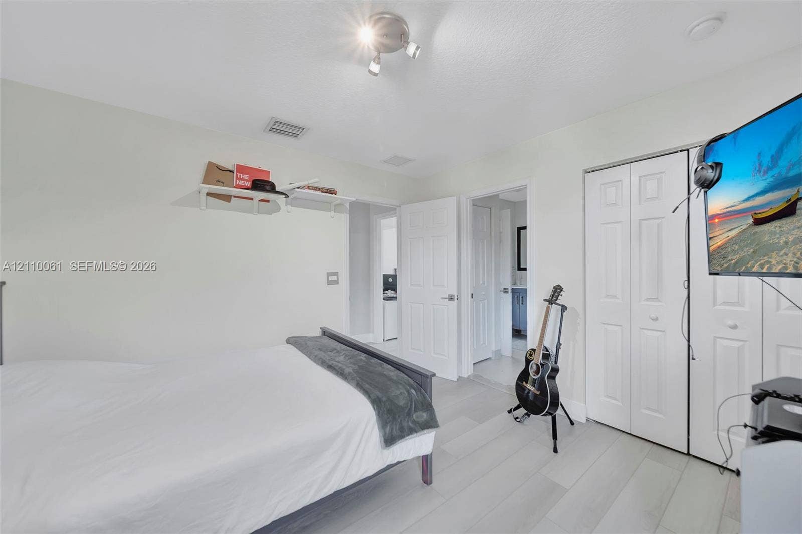4424 E Whitewater Avenue, Weston, FL 33332 Neutral-toned wood-finish flooring, white paneled closet doors, adjustable multi-head track lighting, and built-in wall shelving
