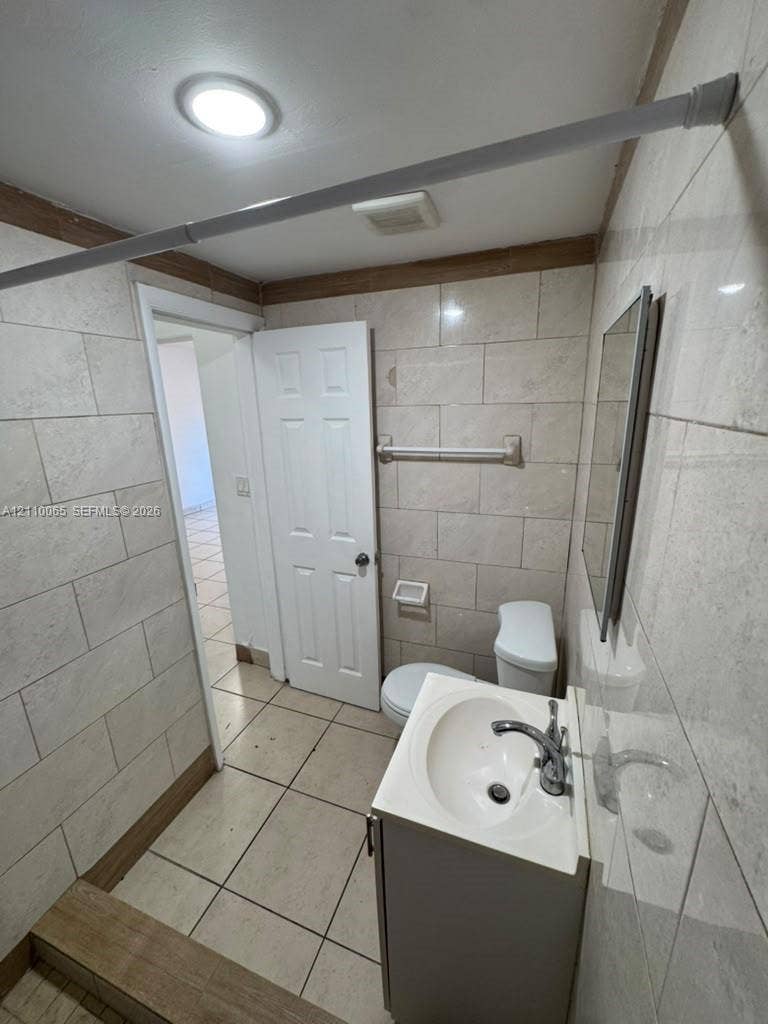 1701 NW 27th Avenue, #14, Miami, Miami, FL 33125 Bathroom featuring light-toned, large-format wall tile, floor tile, a white vanity with an integrated sink, and a wall-mounted mirror