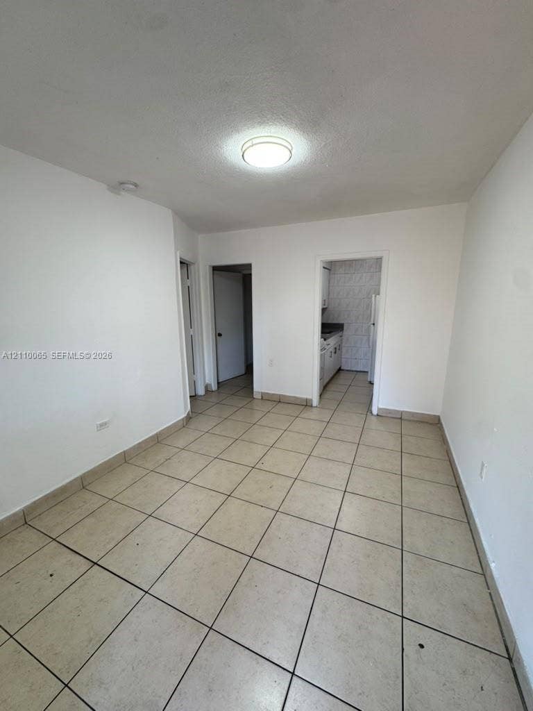 1701 NW 27th Avenue, #14, Miami, Miami, FL 33125 Interior space featuring large-format neutral tile flooring, smooth wall finishes, and a central flush-mount ceiling light fixture