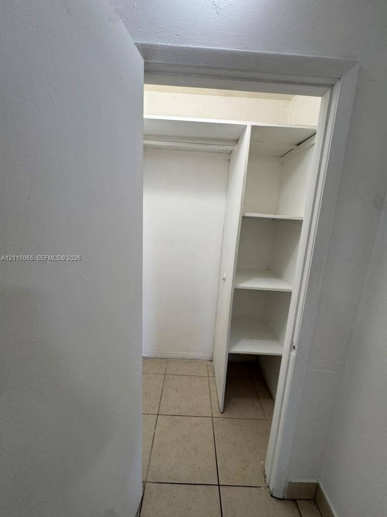 1701 NW 27th Avenue, #14, Miami, Miami, FL 33125 Storage area featuring tile flooring, built-in shelving, and a hanging rod
