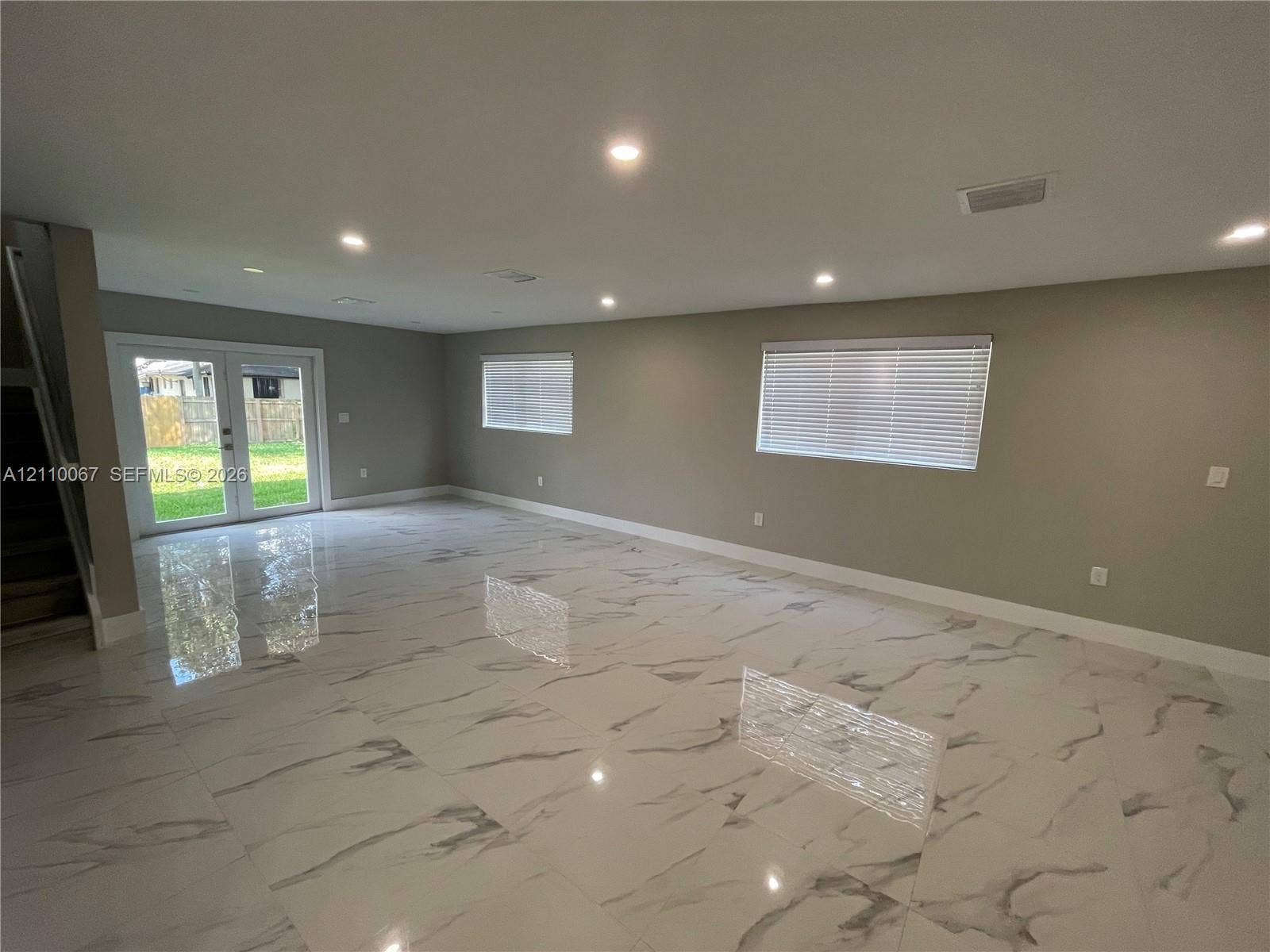 Kitchen featuring high-gloss white cabinetry, stone-finish countertops, stainless steel appliances, a double-basin undermount sink, and tile flooring with a veined pattern