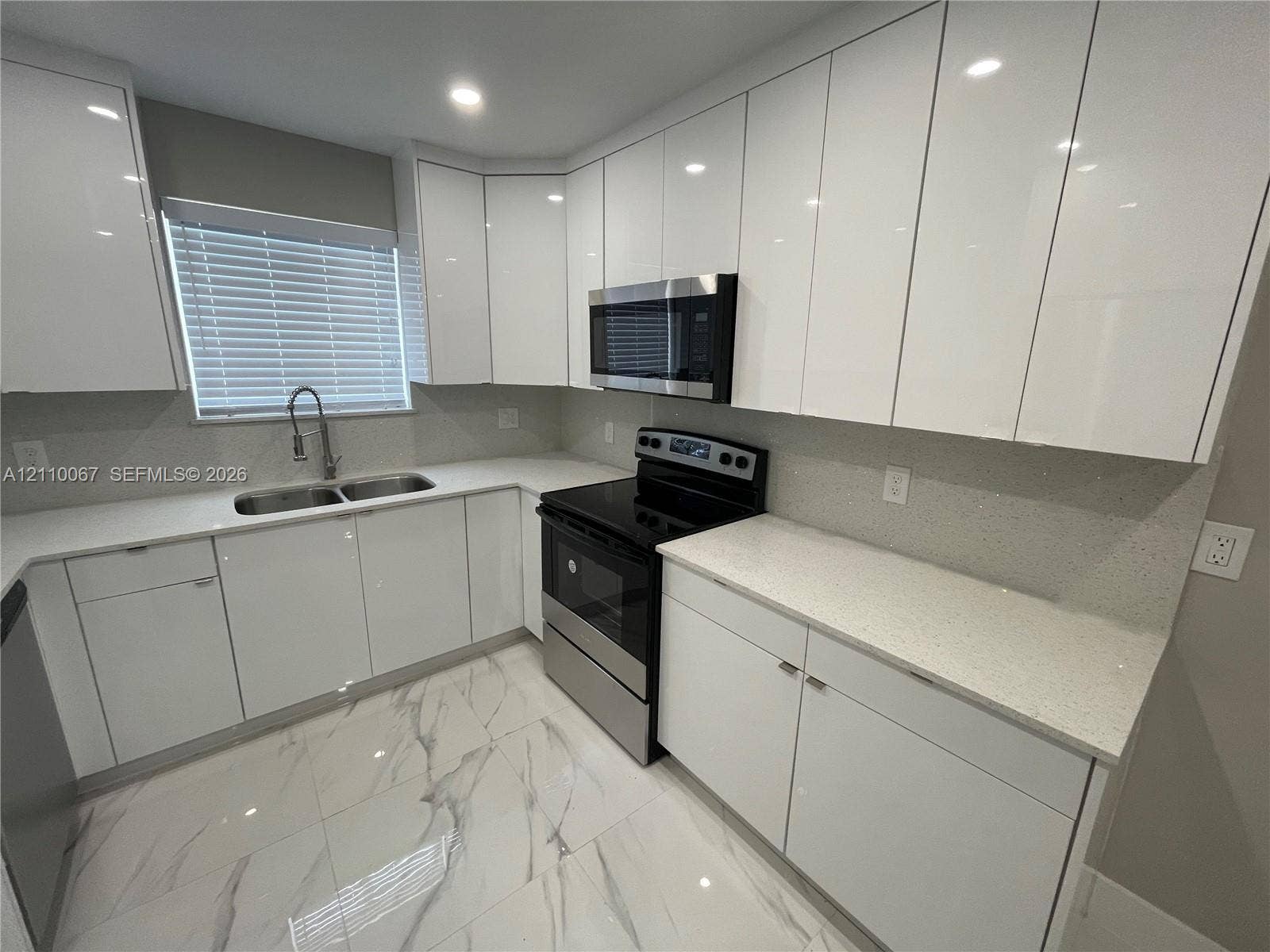 Kitchen featuring high-gloss white cabinetry, white stone-finish countertops, large-format tile flooring, stainless steel side-by-side refrigerator, and recessed ceiling lighting