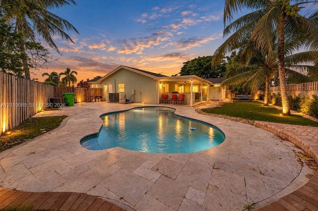 4325 NW 95th Terrace, Sunrise, FL 33351 Outdoor living area featuring a freeform swimming pool, stone paver patio, covered lanai, and fenced perimeter