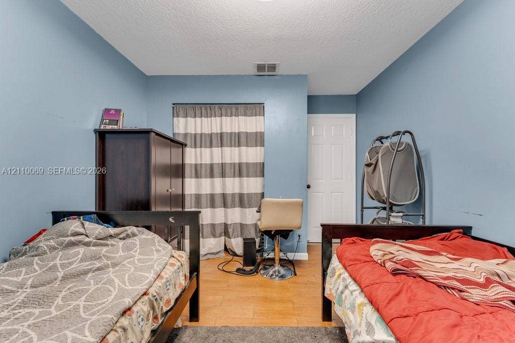 4325 NW 95th Terrace, Sunrise, FL 33351 Room featuring wood-finish flooring, a six-panel interior door, and a built-in closet with sliding curtain closure