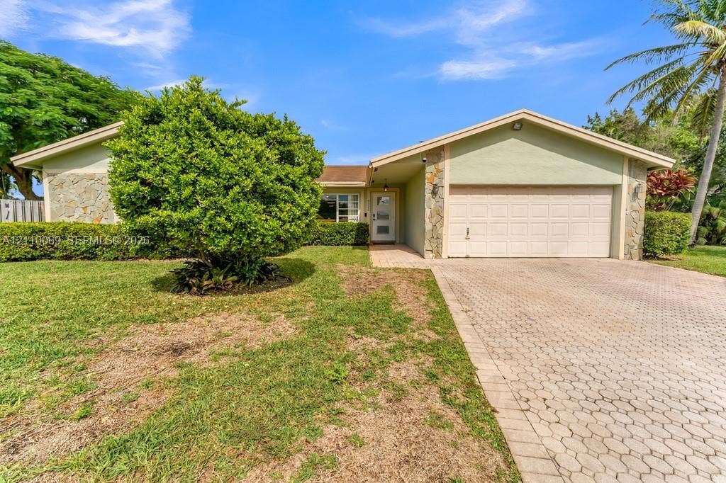4325 NW 95th Terrace, Sunrise, FL 33351 Single-story exterior featuring stone veneer accents, a multi-pane glass entry door, and a paved driveway