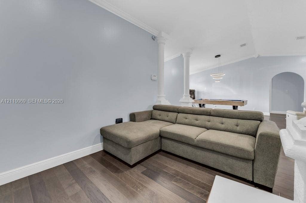 4325 NW 95th Terrace, Sunrise, FL 33351 Interior space featuring wood-finish flooring, vaulted ceilings, decorative columns, arched doorways, and a modern tiered chandelier