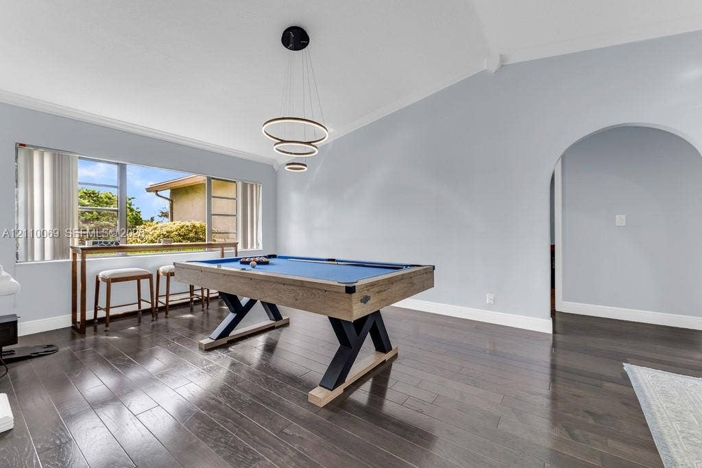 4325 NW 95th Terrace, Sunrise, FL 33351 Vaulted ceilings, wood-finish flooring, architectural arched opening, triple-ring modern chandelier, and oversized window with natural light