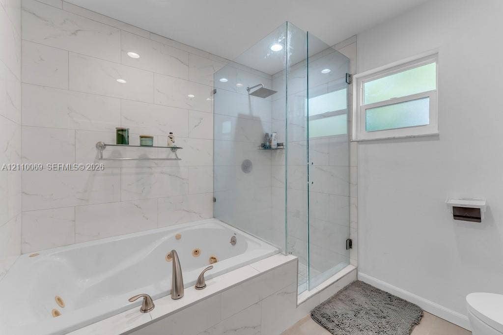 4325 NW 95th Terrace, Sunrise, FL 33351 Jetted soaking tub, walk-in shower with a glass enclosure, oversized wall tiling, and a rainfall showerhead