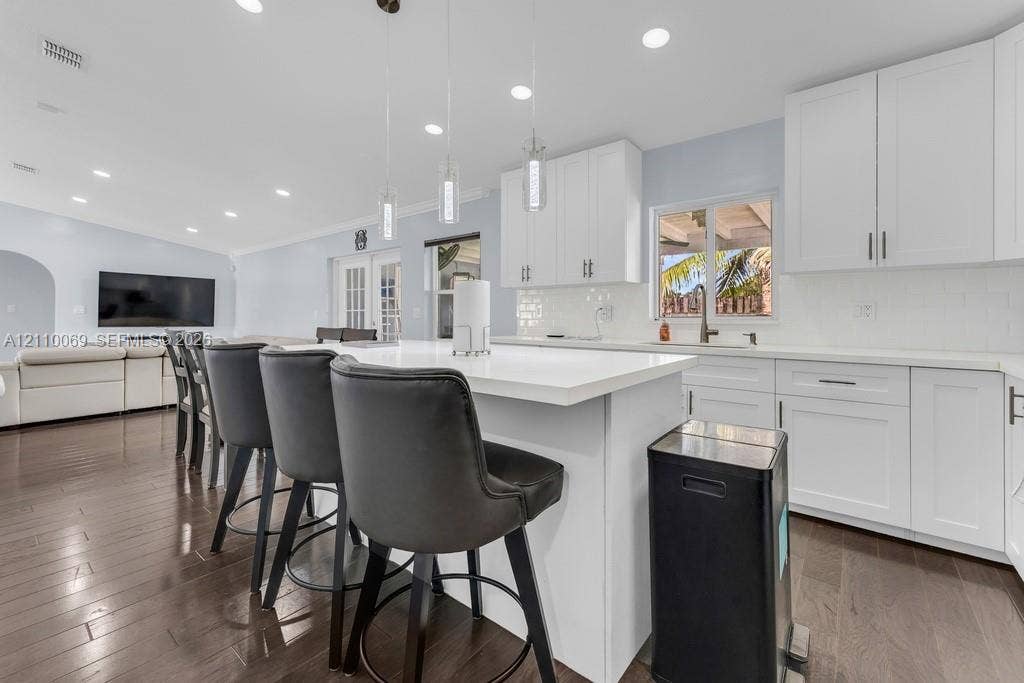 4325 NW 95th Terrace, Sunrise, FL 33351 Kitchen featuring white shaker-style cabinetry, quartz countertops, a central island, recessed lighting, and wood-finish flooring