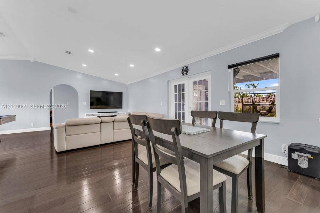 4325 NW 95th Terrace, Sunrise, FL 33351 Open living space featuring dark wood-finish flooring, recessed lighting, crown molding, an arched entryway, and double French doors