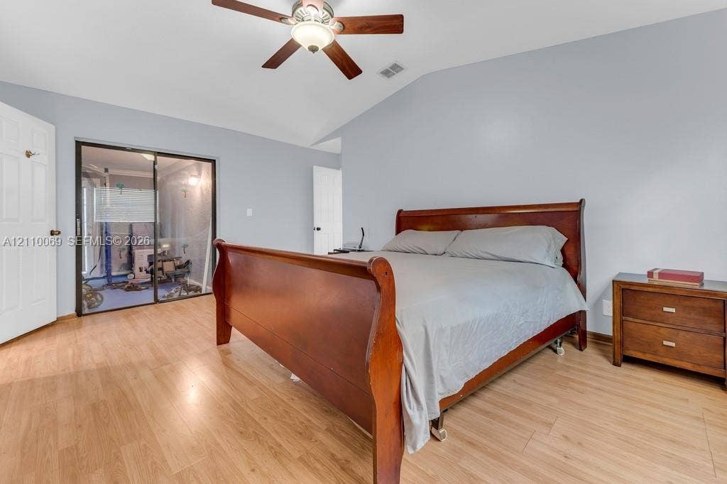 4325 NW 95th Terrace, Sunrise, FL 33351 Vaulted ceiling with integrated wooden-finish ceiling fan, wood-finish flooring, and sliding glass mirror-panel closet doors