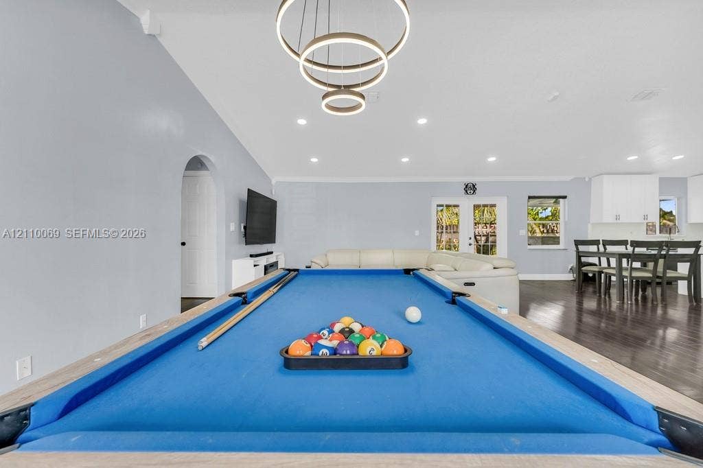 4325 NW 95th Terrace, Sunrise, FL 33351 Open-concept interior featuring recessed lighting, modern tiered ring chandelier, dark wood-finish flooring, and glass-paned double doors