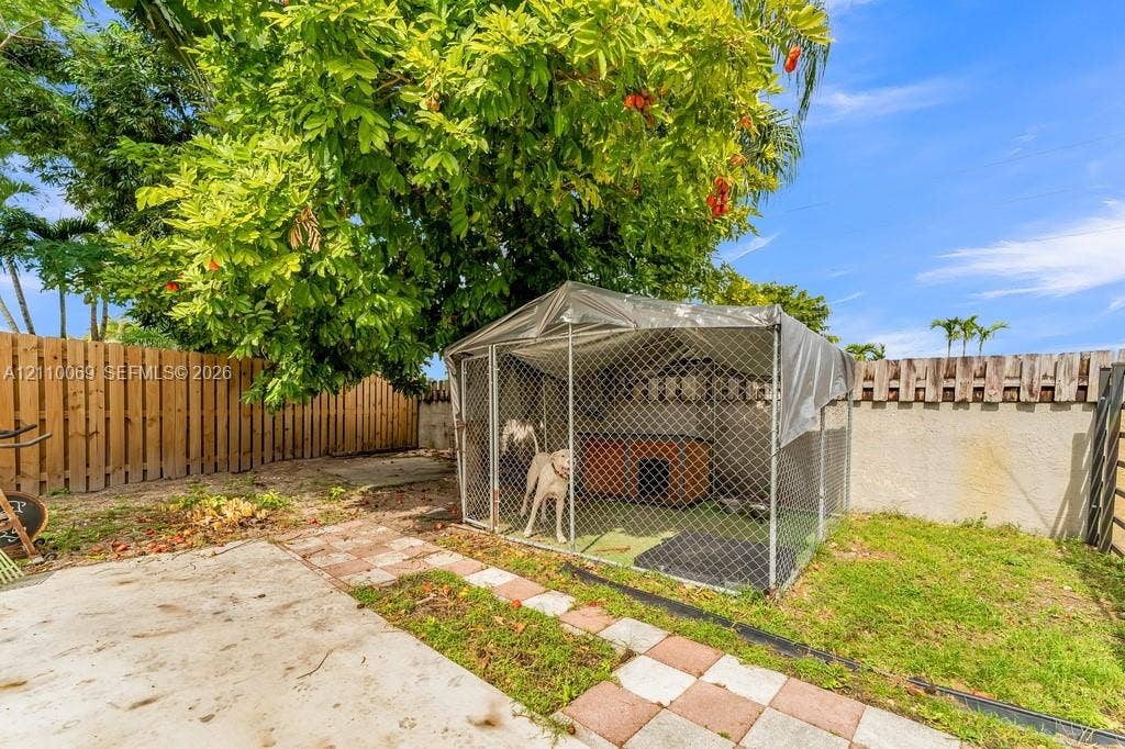 4325 NW 95th Terrace, Sunrise, FL 33351 Private backyard featuring a fenced enclosure, concrete patio, decorative paver border, and mature perimeter trees