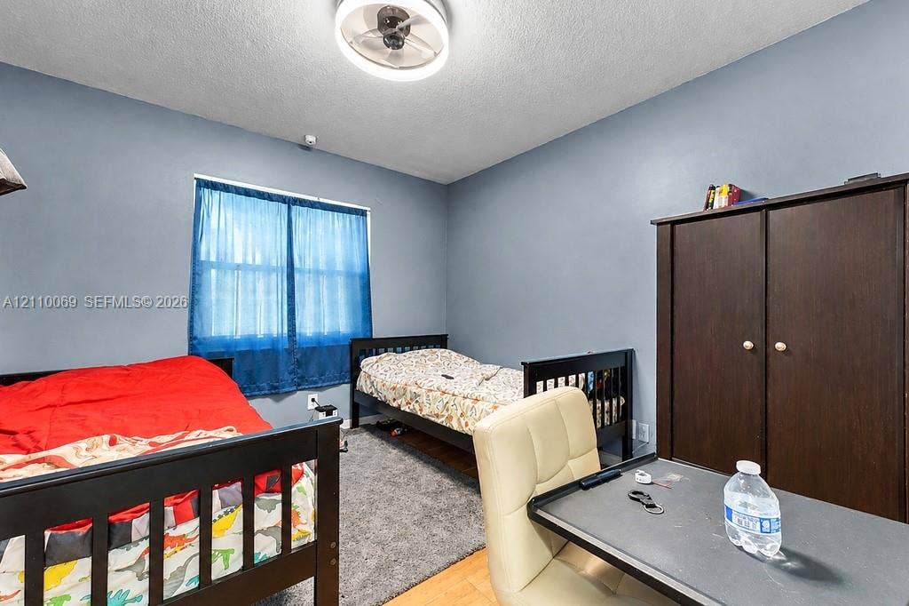 4325 NW 95th Terrace, Sunrise, FL 33351 Neutral-toned room featuring a central ceiling-mounted light fixture and dual-surface flooring consisting of textile carpet and wood-finish planks