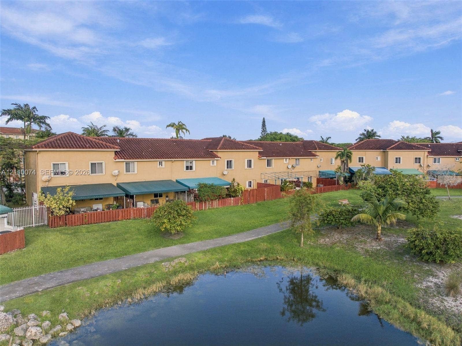 17370 NW 69th Court, #304, Hialeah, FL 33015 Multi-story stucco exterior featuring a tile roof, dedicated green space, paved pathways, and a water feature
