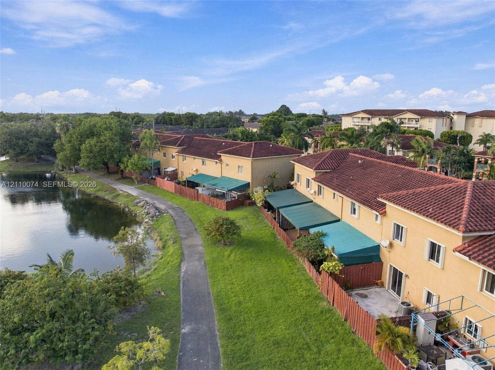 17370 NW 69th Court, #304, Hialeah, FL 33015 Multi-unit residential complex featuring terracotta-style tile roofing, stucco exterior finish, paved pedestrian pathways, and a water feature