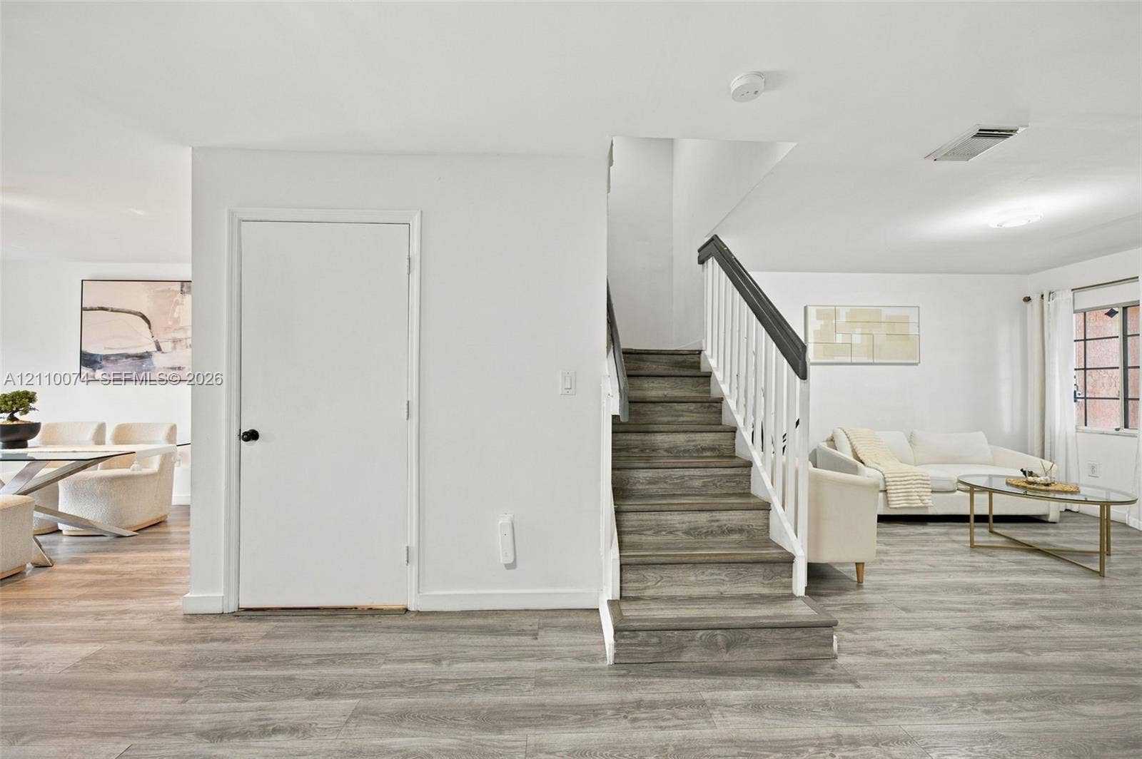 17370 NW 69th Court, #304, Hialeah, FL 33015 Staircase featuring white balusters and a dark-toned handrail, wood-finish flooring, and a multi-pane window