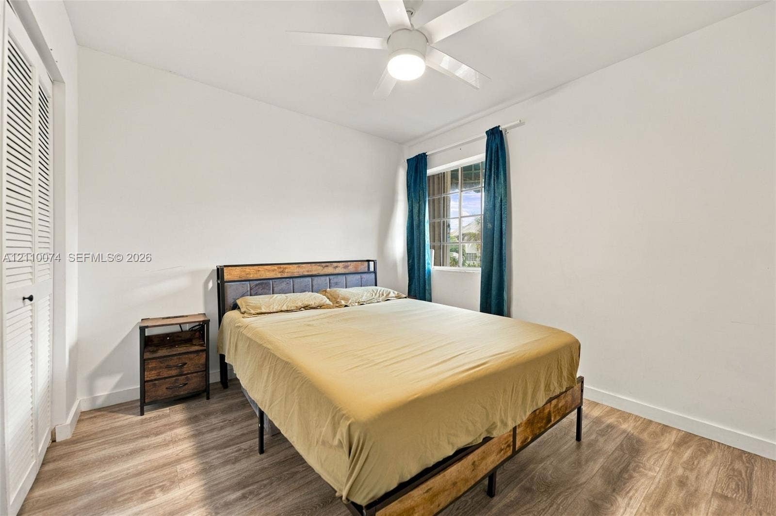 17370 NW 69th Court, #304, Hialeah, FL 33015 Bedroom featuring wood-finish flooring, a white ceiling fan with integrated lighting, and closet doors with louvered panels