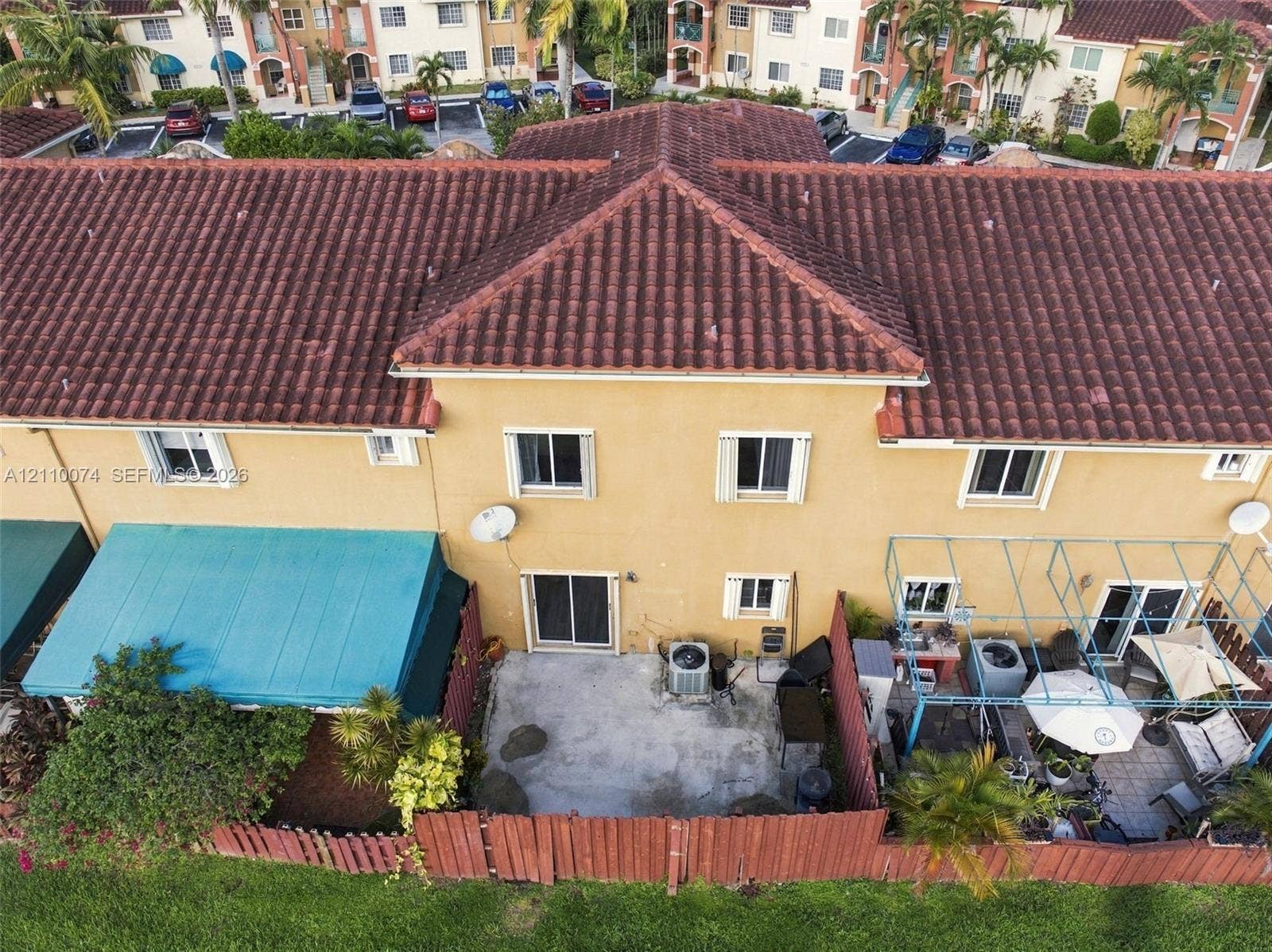 17370 NW 69th Court, #304, Hialeah, FL 33015 Two-story exterior with clay tile roofing, stucco finish, sliding glass doors, and a private rear patio enclosed by wood fencing