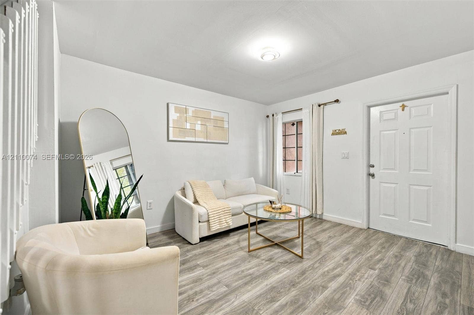 17370 NW 69th Court, #304, Hialeah, FL 33015 Neutral-toned interior space featuring wood-finish flooring, a six-panel entry door, and a multi-pane window with installed hardware