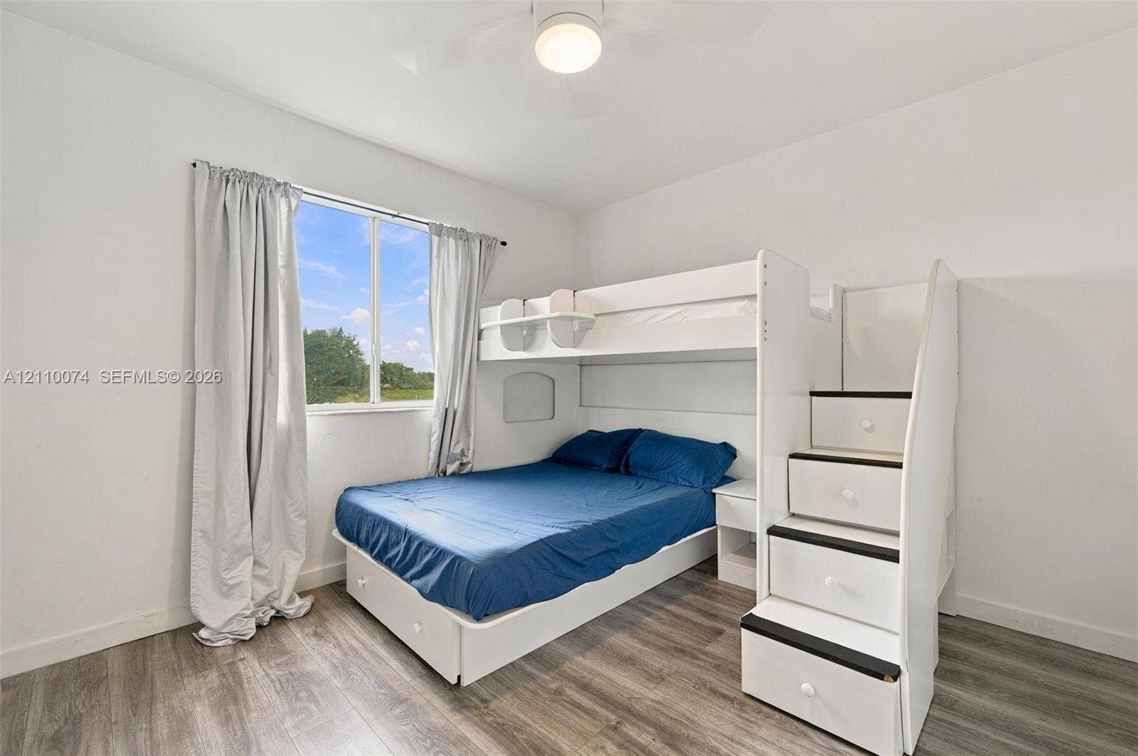 17370 NW 69th Court, #304, Hialeah, FL 33015 Neutral-toned room featuring wood-finish flooring, a single-pane window, and a ceiling-mounted light fixture