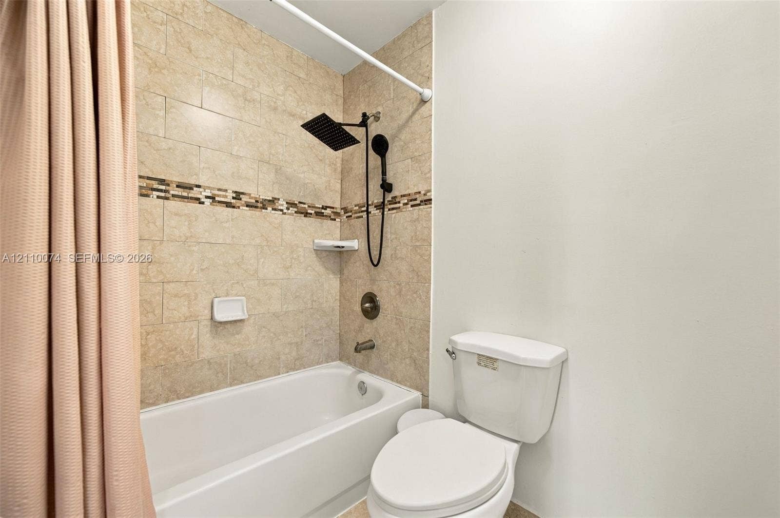 17370 NW 69th Court, #304, Hialeah, FL 33015 Full bathroom featuring a shower-tub combination with large-format wall tile, decorative tile inlay, a matte black rainfall showerhead, and a matching handheld sprayer