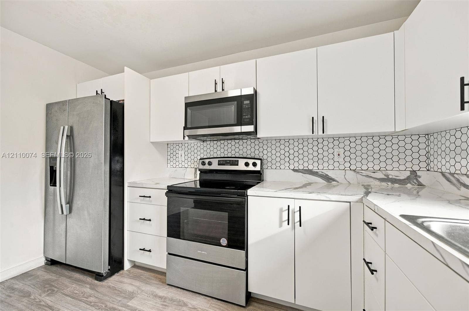 17370 NW 69th Court, #304, Hialeah, FL 33015 Kitchen featuring white cabinetry, stone-look countertops, hexagonal tile backsplash, stainless steel appliances, and wood-finish flooring