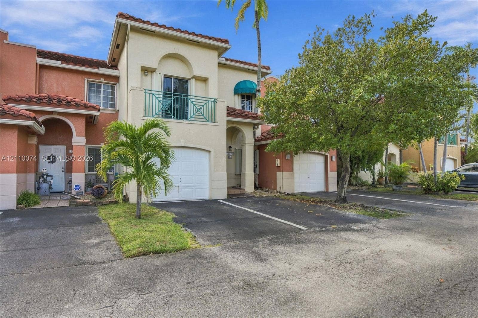 17370 NW 69th Court, #304, Hialeah, FL 33015 Stucco exterior featuring a tile roof, an arched entryway, a second-story balcony with metal railing, and an attached single-car garage