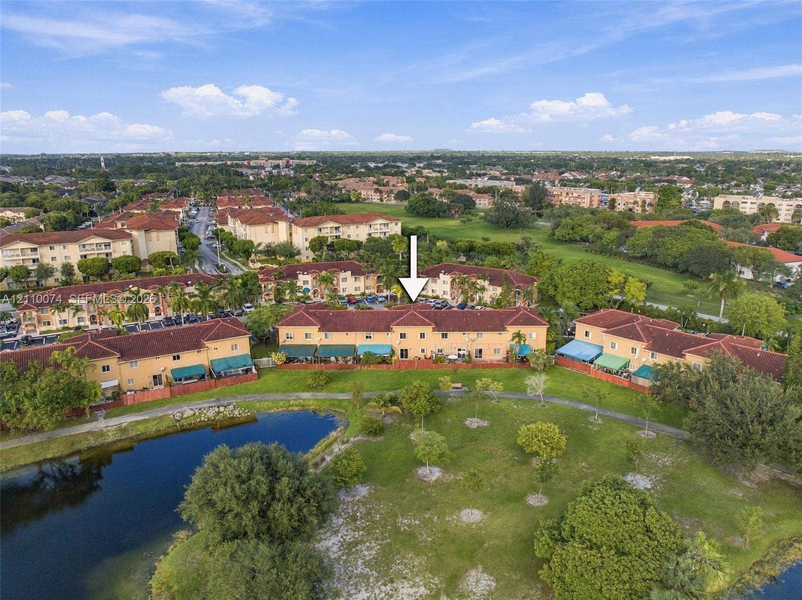 17370 NW 69th Court, #304, Hialeah, FL 33015 Aerial perspective of a multi-unit complex featuring terra cotta-style shingle roofing, stucco exterior, and waterfront grounds with a paved walking path