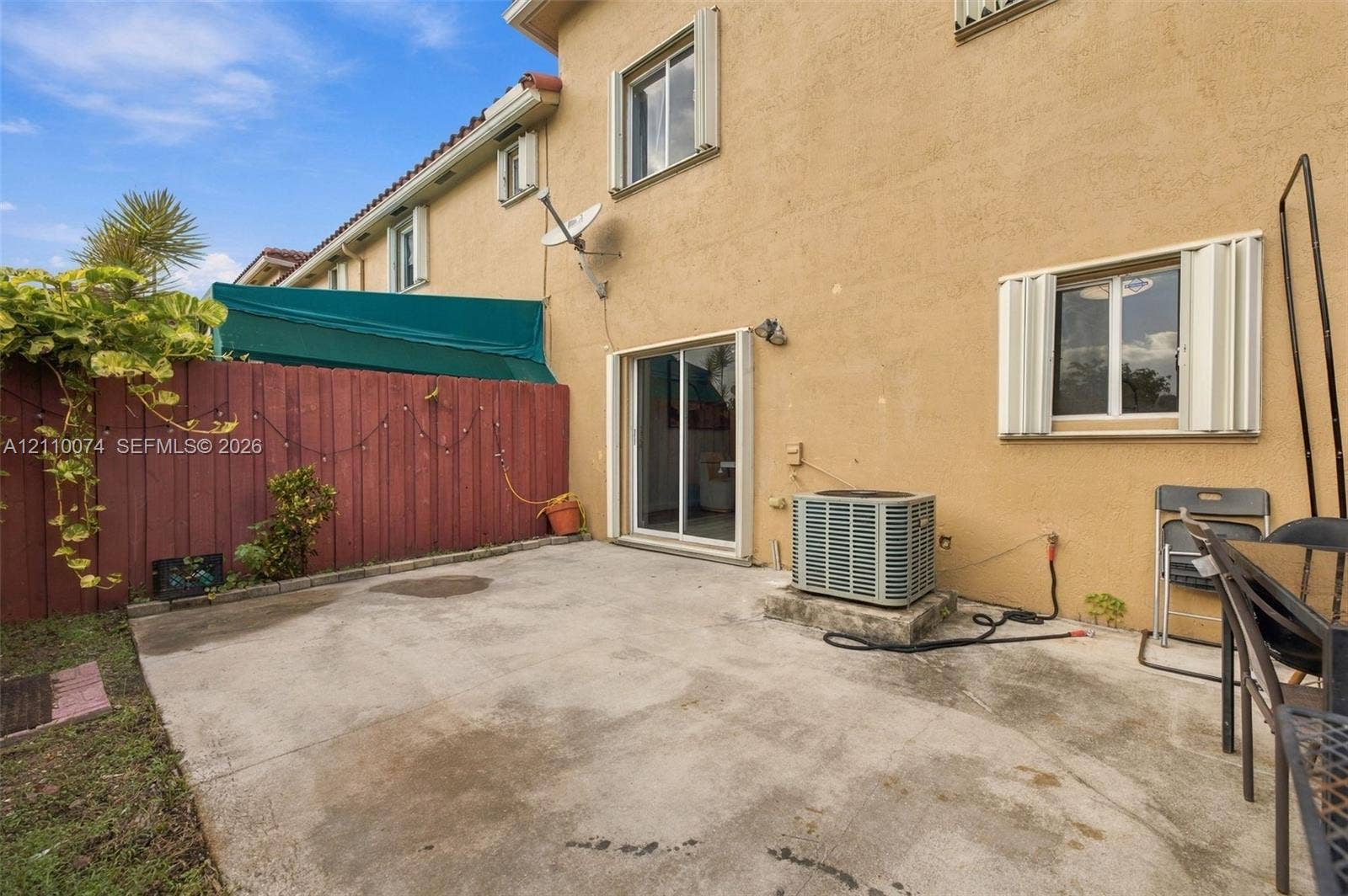 17370 NW 69th Court, #304, Hialeah, FL 33015 Concrete patio area enclosed by a wood privacy fence featuring sliding glass door access and exterior shutters