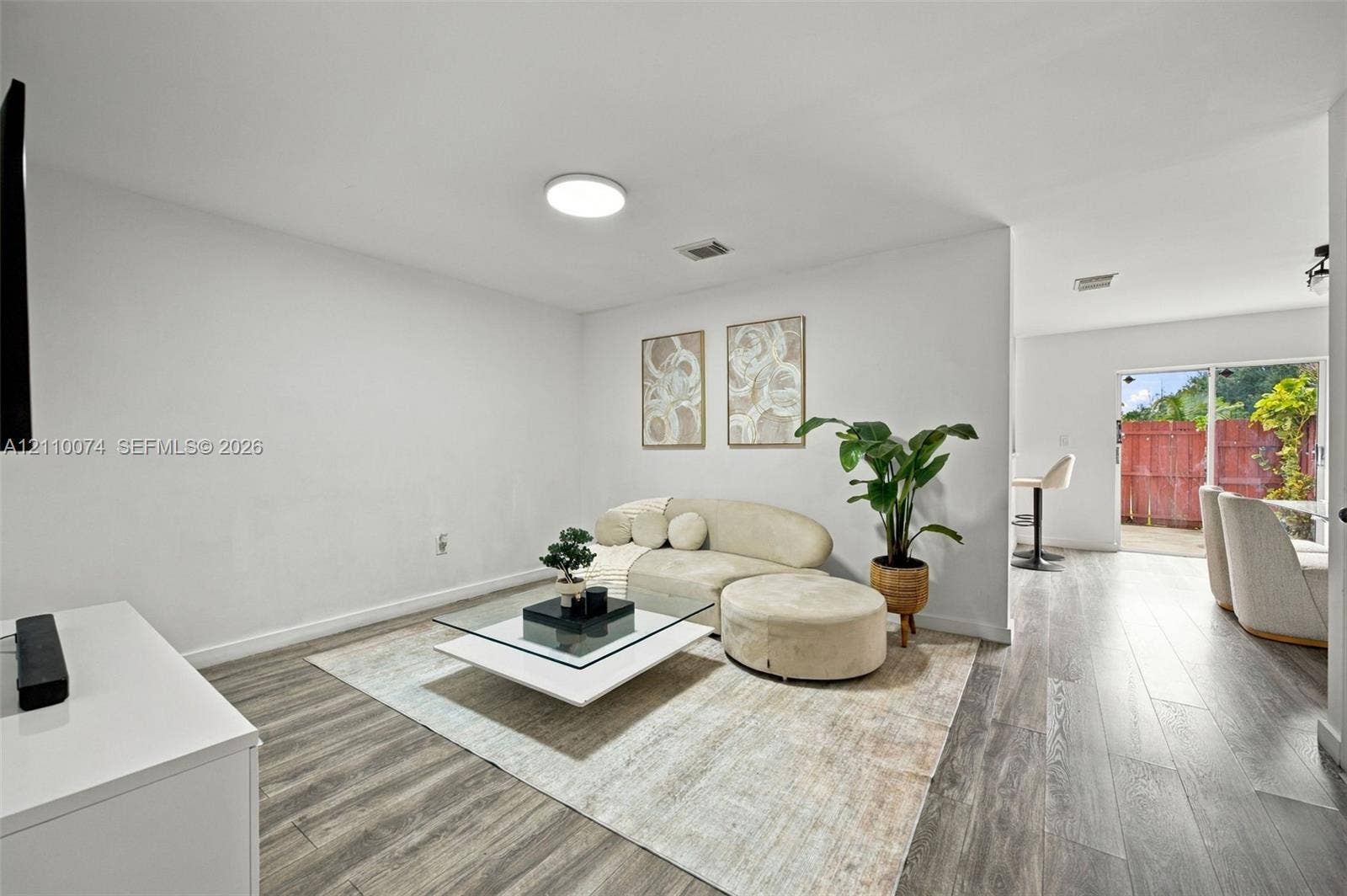 17370 NW 69th Court, #304, Hialeah, FL 33015 Neutral-toned interior featuring wood-finish flooring, recessed lighting, and a glass sliding door providing outdoor access