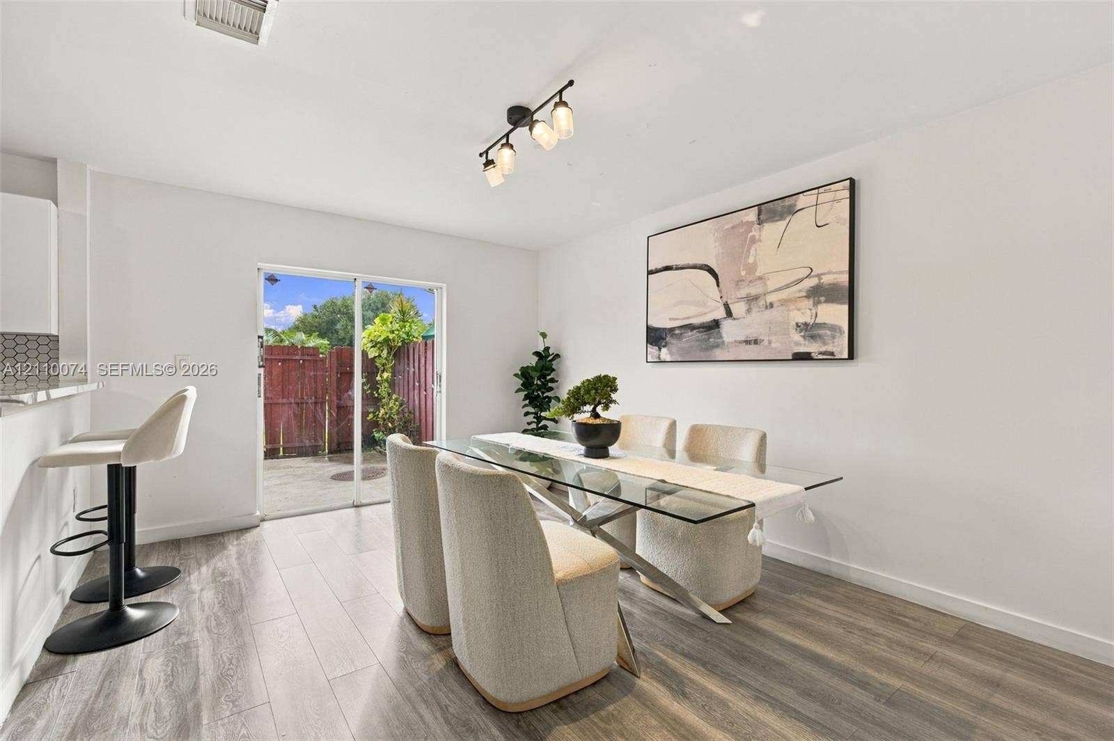 17370 NW 69th Court, #304, Hialeah, FL 33015 Dining area featuring wood-finish flooring, a multi-bulb ceiling fixture, a breakfast bar, and sliding glass doors with exterior access