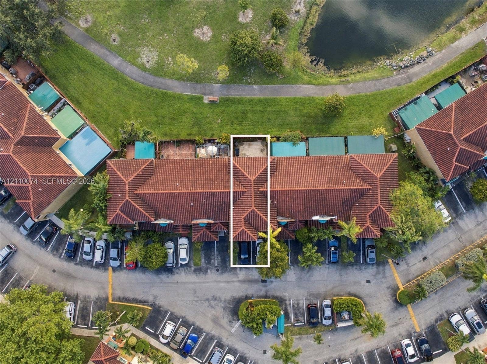 17370 NW 69th Court, #304, Hialeah, FL 33015 Aerial perspective of multi-family residence featuring a clay tile roof, dedicated parking spaces, and a rear patio area bordering a community pond and walking path