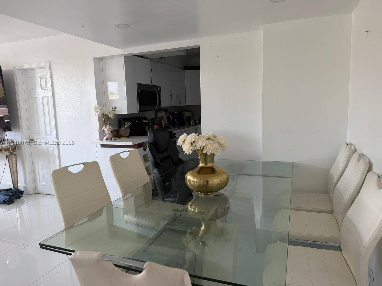2017 S Ocean Drive, #208, Hallandale Beach, Hallandale Beach, FL 33009 Dining area featuring high-gloss tile flooring, recessed ceiling lighting, and a neutral color palette, opening to a kitchen equipped with white cabinetry and a built-in microwave