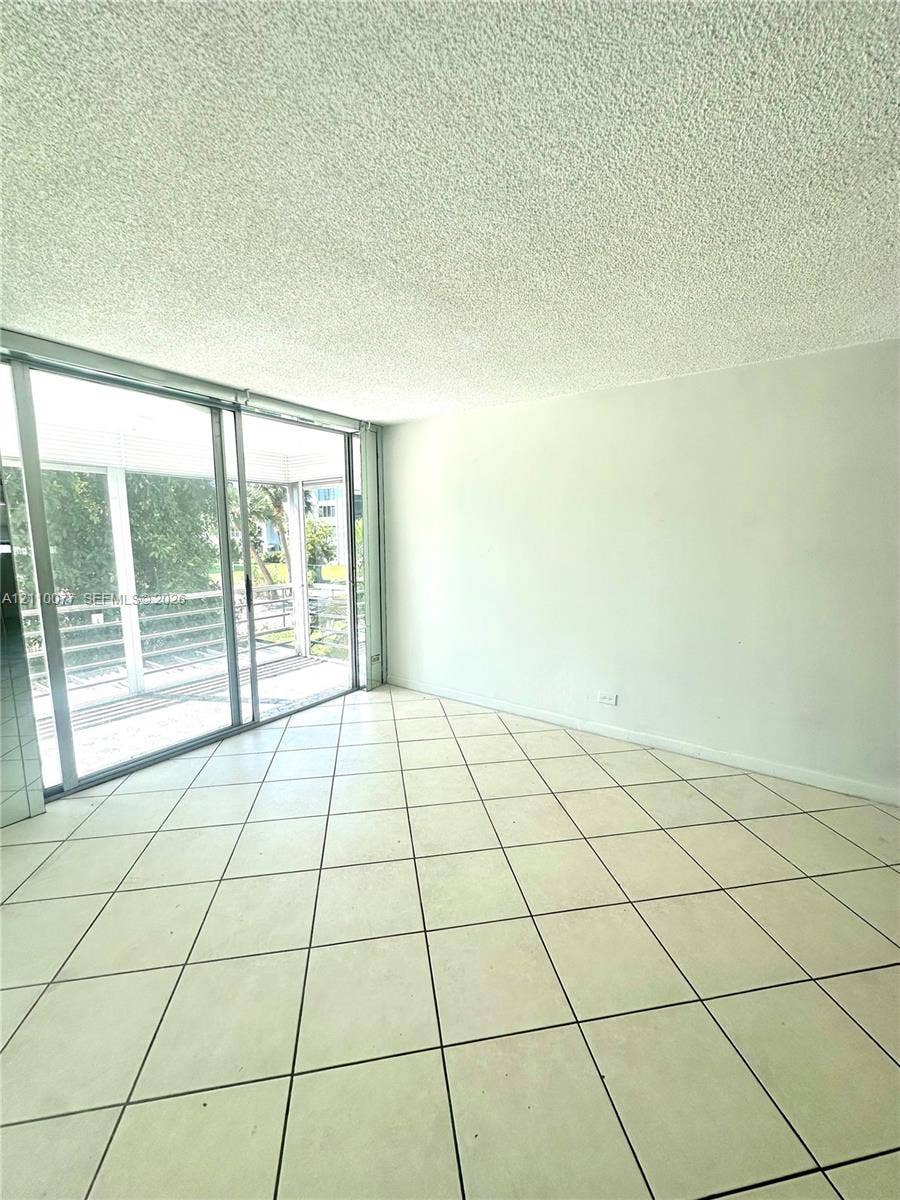 Living area featuring floor-to-ceiling sliding glass doors and ceramic tile flooring