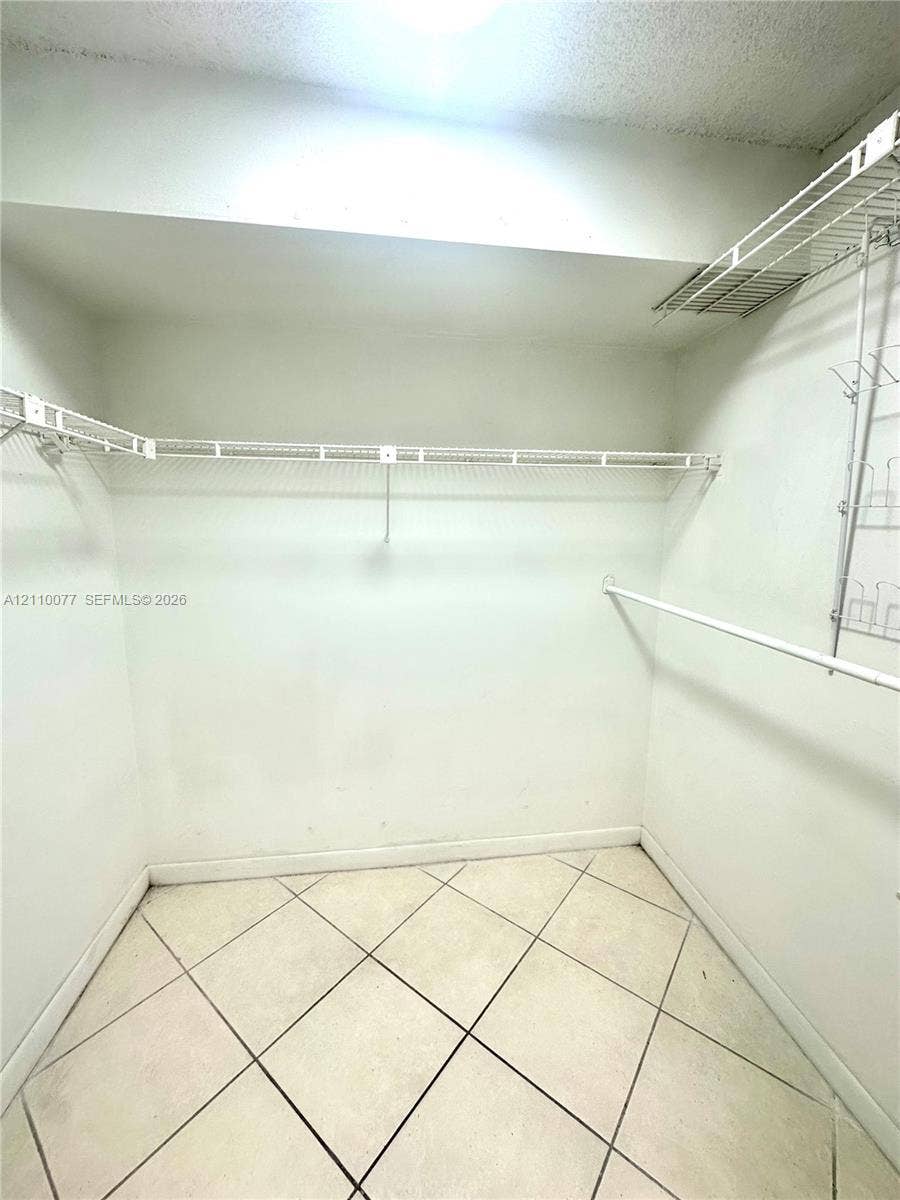 Walk-in closet featuring light-toned tile flooring and multi-level white wire shelving