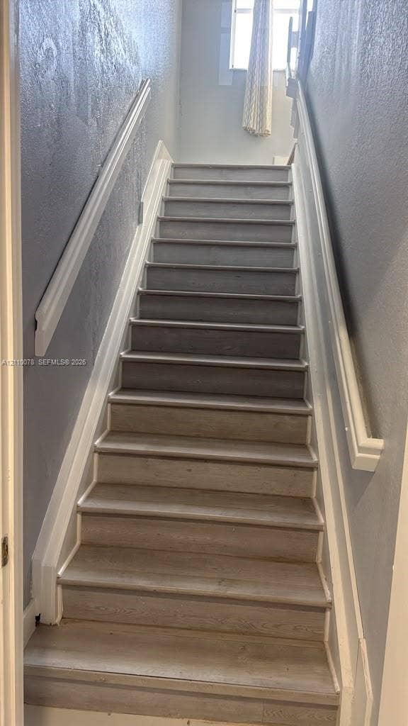 Staircase featuring wood-finish treads and white painted handrails