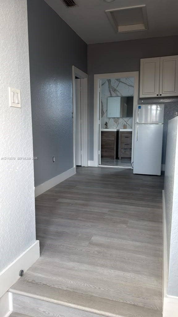Wood-finish flooring, upper cabinetry, and solid surface bathroom vanity with dual sinks