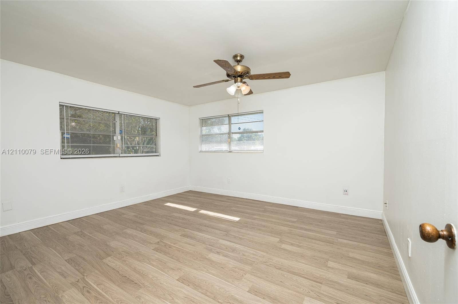 4106 NW 88th Avenue, #3, Coral Springs, FL 33065 Interior space featuring wood-finish flooring, dual windows with horizontal blinds, and a central ceiling fan with an integrated light fixture