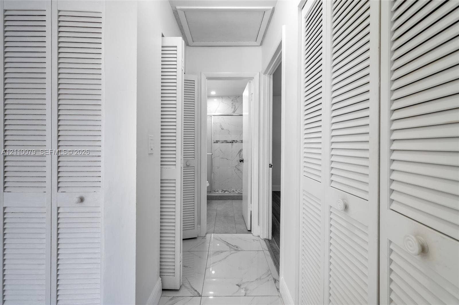 4106 NW 88th Avenue, #3, Coral Springs, FL 33065 Hallway featuring large-format tile flooring with a neutral finish, multiple white louvered-style closet doors, and recessed ceiling lighting