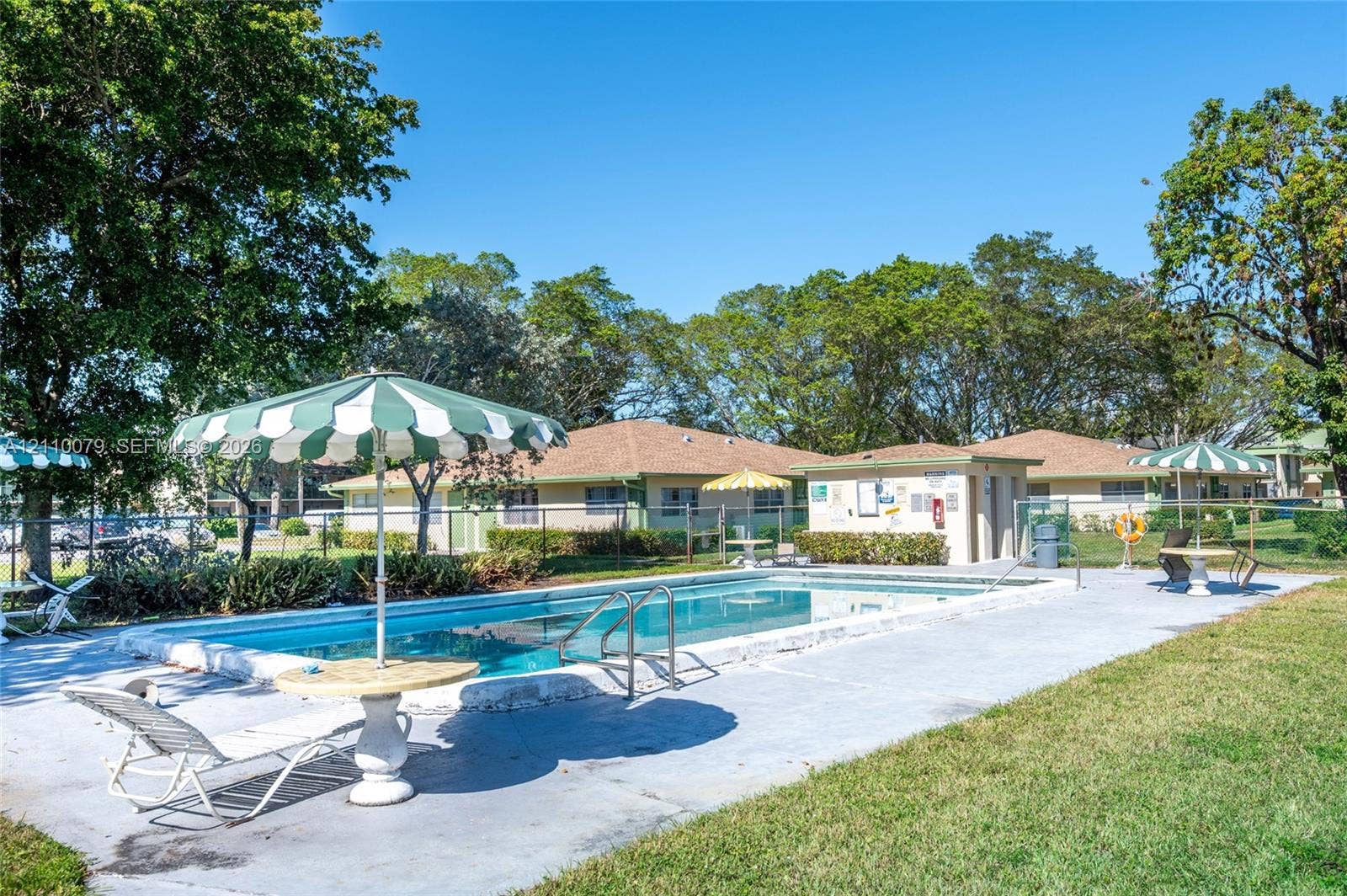 4106 NW 88th Avenue, #3, Coral Springs, FL 33065 Outdoor swimming pool featuring a concrete deck and metal perimeter fencing, surrounded by mature trees