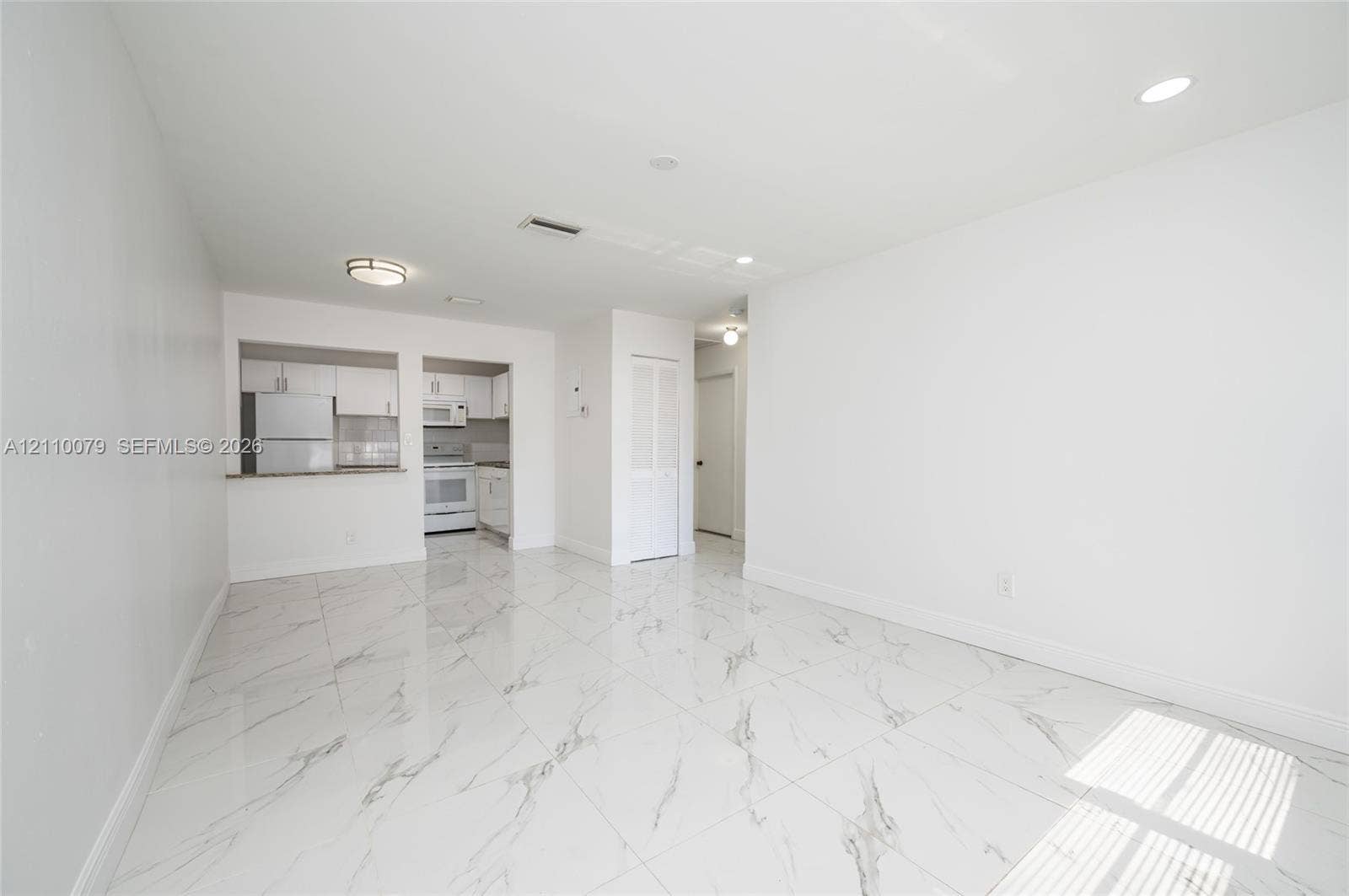 4106 NW 88th Avenue, #3, Coral Springs, FL 33065 Large-format tile flooring with veining, white cabinetry, integrated pass-through, recessed lighting, and flush-mount ceiling fixture