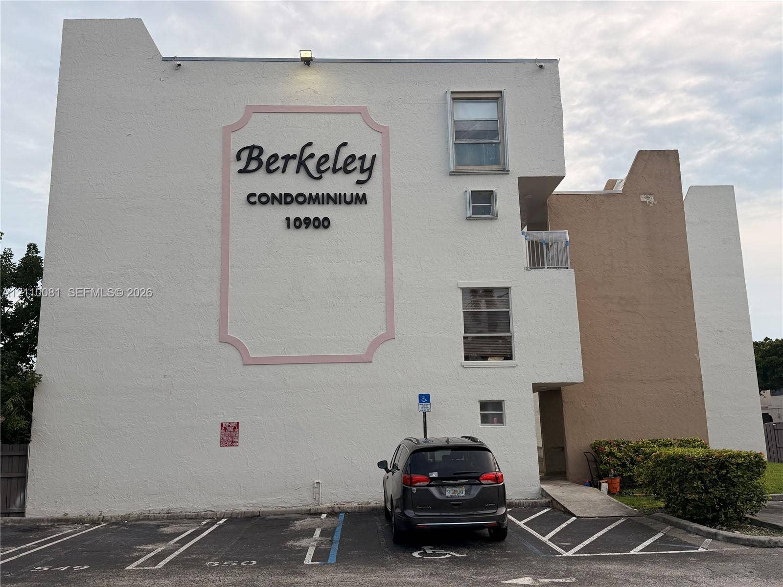 Exterior facade featuring a stucco finish, multi-level building design, dedicated parking stalls, and paved access ramp
