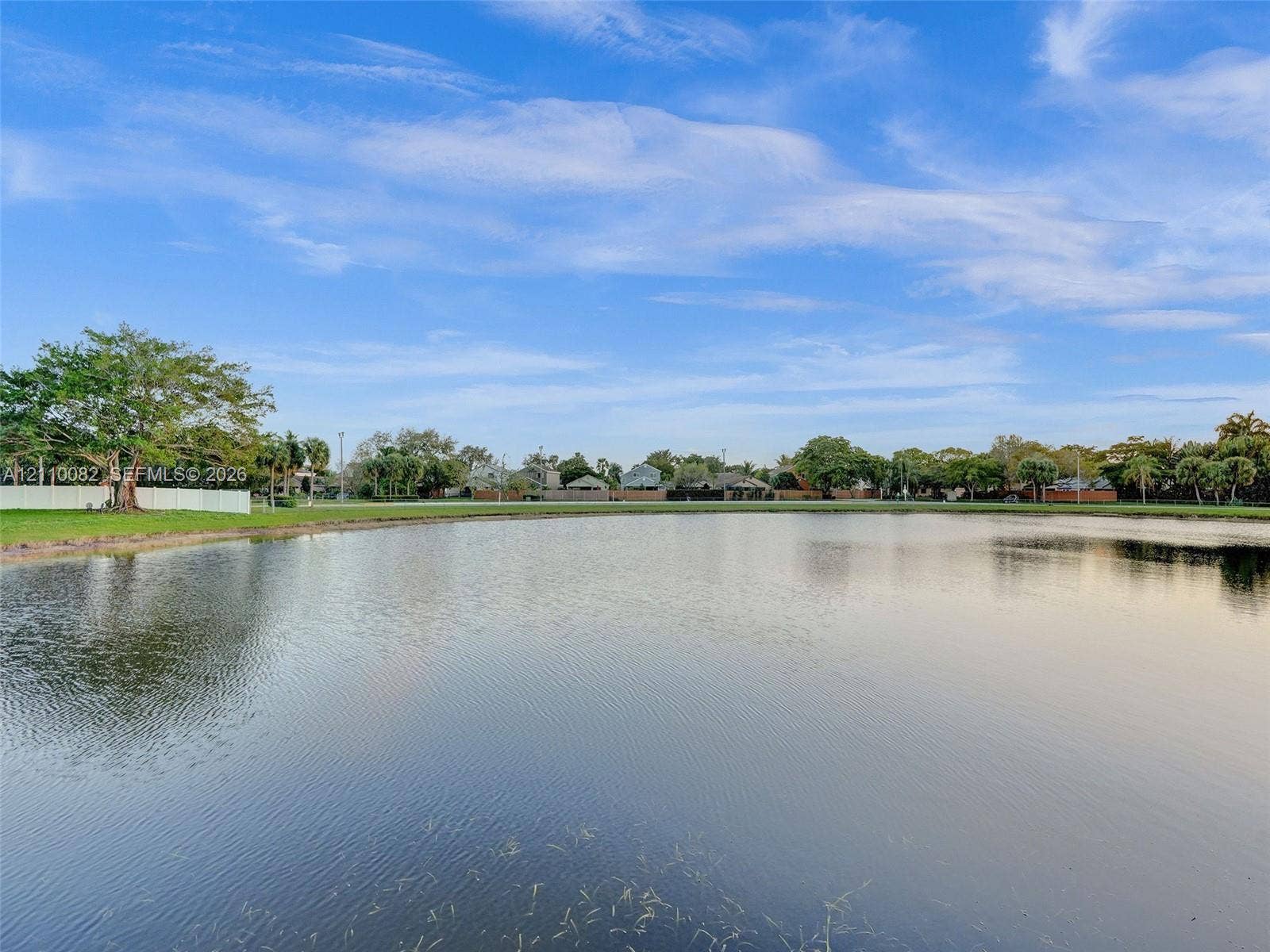 Waterfront lot featuring a wide expanse of open water, manicured grass perimeter, and mature trees