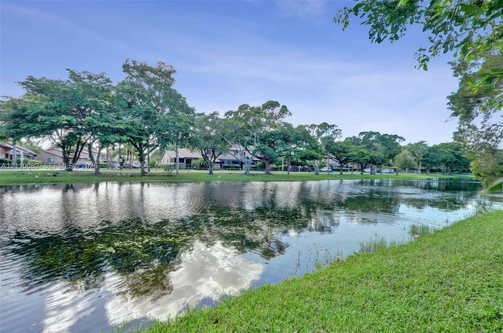 Waterfront property featuring a canal, expansive lawn, and mature trees