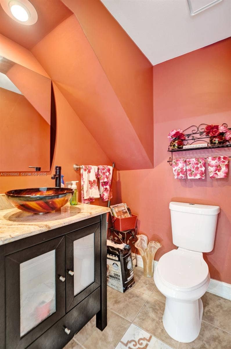 Vanity featuring a dark wood-finish cabinet with glass panel doors, stone-composite countertop, and a decorative circular glass vessel sink with a wall-mounted faucet